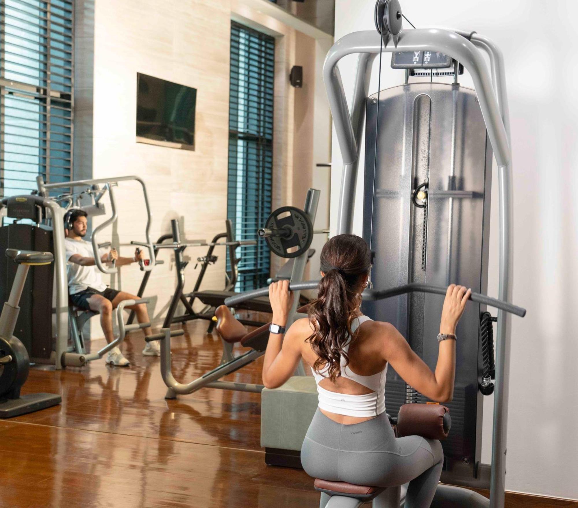 Fairmont Riaad Buitenkant foto A woman using a lat pulldown machine